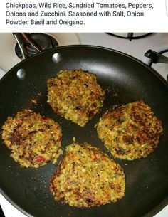 four burgers cooking in a frying pan on top of a stove burner