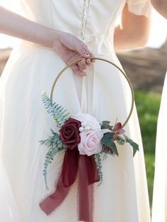 a woman in a white dress holding a red and pink flower arrangement on her wedding day