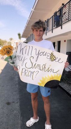 a young man holding a sign that says will you see my sunshine from here?