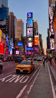 a city street filled with lots of traffic and tall buildings covered in billboards at dusk