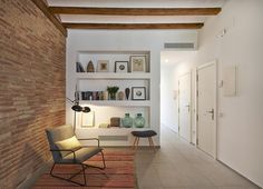 a living room with a brick wall and shelves on the wall, along with a modern chair