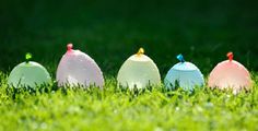 four plastic eggs sitting in the grass on top of each other