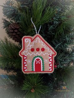 a gingerbread house ornament hanging from a christmas tree