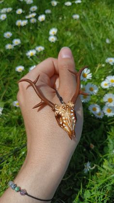 a hand is holding a small insect on it's arm in front of some daisies