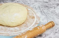 a ball of dough sitting on top of a blue plate next to a rolling pin