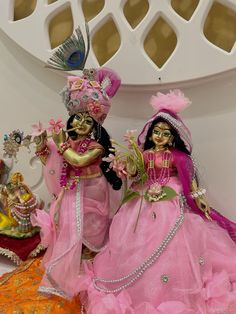 two figurines are dressed in pink and gold