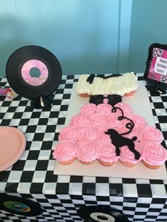 a table topped with cupcakes covered in pink frosting and vinyl record records