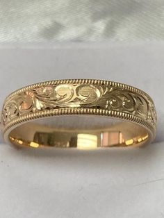 a gold wedding band with filigrees on it