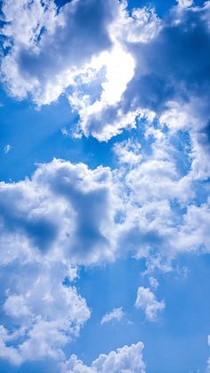 the airplane is flying high in the blue sky with white clouds above it and below