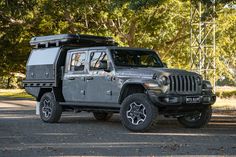 the jeep is parked on the side of the road in front of some tall trees