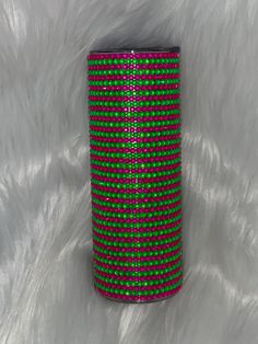 a can with green and pink dots on it sitting on a white fur covered surface