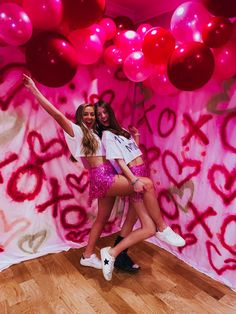 two young women posing for a photo in front of pink and red balloon backdrops