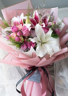 pink and white flowers in a bouquet wrapped in ribbon on top of a tablecloth