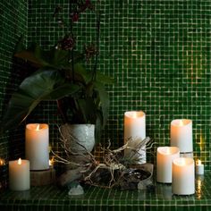 candles are arranged on a green tiled counter