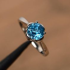 It is a real Swiss blue topaz  ring, round cut, measures 7mm*7mm, weight about 1.68 cts. The basic metal is sterling silver and plated with rhodium.To change the metal to a solid gold (white/rose) or platinum is also available, please ask for a quotation if you want.You can also go to my shop Home for more elegant rings: https://www.etsy.com/shop/godjewelry?ref=hdr_shop_menuSwiss blue topaz is birthstone of NovemberMore Swiss blue topaz rings:https://www.etsy.com/shop/godjewelry?ref=seller-platf Classic Round Topaz Crystal Ring, Classic Topaz Ring With Round Cut, Classic Round Cut Topaz Ring, Classic Round Topaz Birthstone Ring, Blue Topaz Solitaire Crystal Ring, Classic Sterling Silver Topaz Ring With Round Stone, Sterling Silver Solitaire Topaz Promise Ring, Sterling Silver Round Topaz Promise Ring, Classic Topaz Ring With Birthstone In Round Band