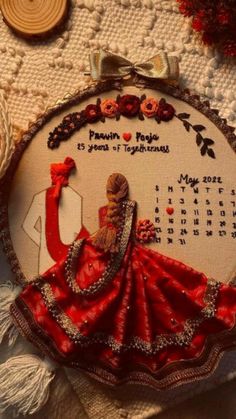 a cross stitch calendar with a woman in a red dress