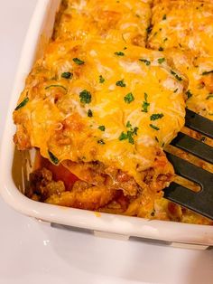 a casserole dish with chicken, cheese and vegetables being lifted by a fork