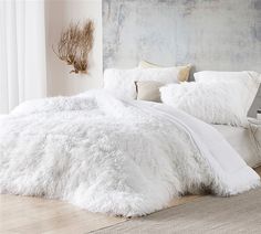 a bed with white fluffy blankets and pillows