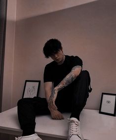 a man sitting on top of a white counter next to a framed photo and shoes