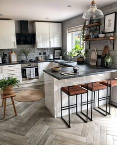 a kitchen with white cabinets and black counter tops, wooden flooring and an island in the middle