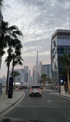 a car driving down a street next to tall buildings and palm trees in the foreground