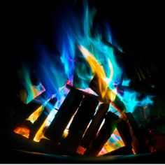 the fire is glowing brightly in the dark with bright blue and yellow flames behind it