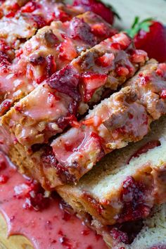 sliced bread with strawberries on top and drizzled with strawberry sauce sitting on a cutting board