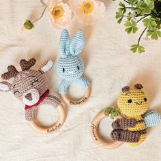 three crocheted animals sitting next to each other on a white sheet with flowers