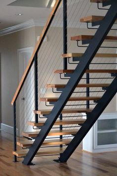 an empty living room with stairs and hard wood flooring