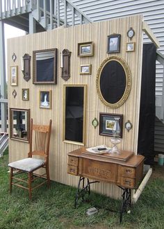 an old fashioned desk and chair in front of a house with pictures on the wall