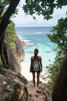 a woman standing on top of a cliff next to the ocean