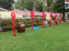 red and white decorations are on the grass in front of barrels with flags hanging from them