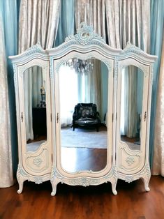 an ornate white armoire with mirrors on it