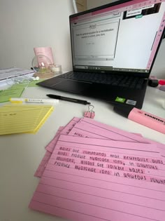 a laptop computer sitting on top of a desk covered in pink sticky notes and pens