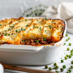 a casserole dish with meat and vegetables in it on a white tablecloth