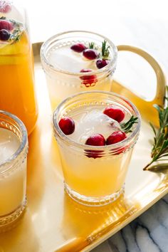 three glasses filled with lemonade and cranberries on top of a gold tray