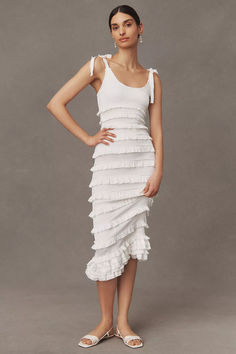 a woman is wearing a white dress with ruffles