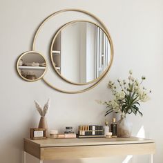 a wooden table topped with a mirror next to a vase filled with flowers