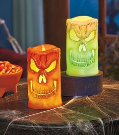 three halloween candles sitting on top of a table next to a bowl full of candy