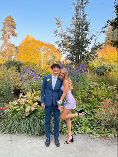 a young man and woman posing for a photo in front of some colorful flowers at their wedding