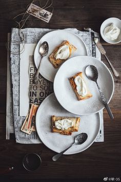 two white plates topped with desserts on top of a wooden table next to utensils