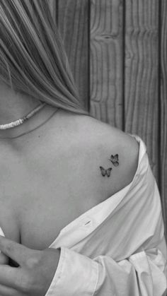 a woman with a small butterfly tattoo on her back shoulder and left arm, in black and white