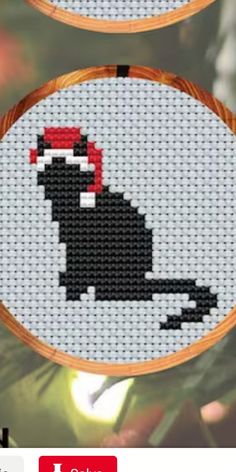 two cross stitch christmas ornament designs on a white background, one with a red santa hat and the other with a black cat