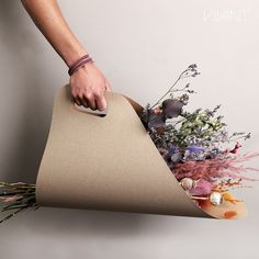 a person is holding a bouquet of flowers in a paper bag that looks like a cone