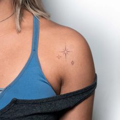 a woman with a cross tattoo on her left upper arm and shoulder, wearing a blue tank top