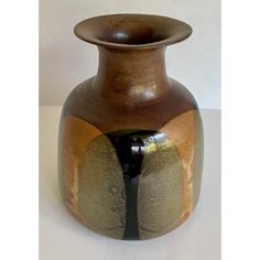 a brown vase sitting on top of a white table