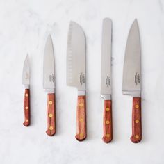 four knives are lined up next to each other on a white counter top with yellow dots