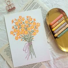 some crayons are sitting on top of an open book with a bouquet of flowers