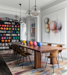 a dining room with colorful balls on the table and bookshelves in the background