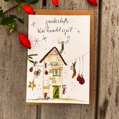 a christmas card with a house and stockings hanging on a clothes line, surrounded by red flowers